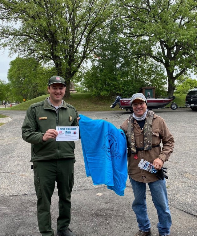 Hunter Simonson, park ranger, presents a beach towel to a visitor wearing a life jacket at Sandy Lake Recreation Area, near McGregor, Minnesota, May 27.