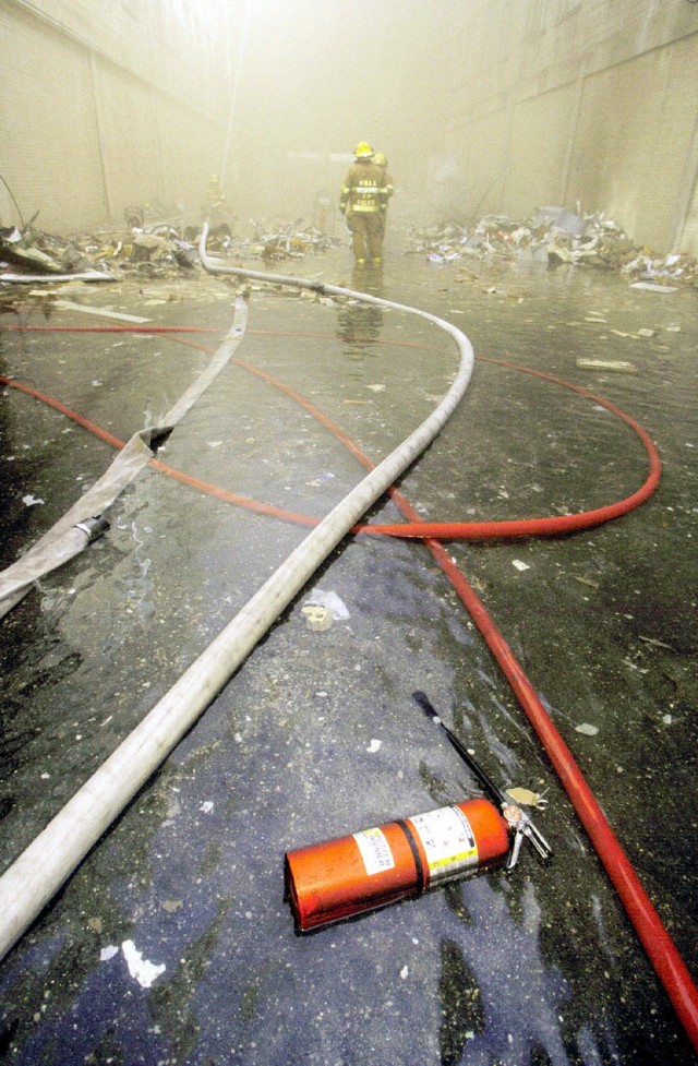 Early fire fighting methods shown in the aftermath of a hijacked American Airlines Flight 77, that impacted the Pentagon killing all 64 passengers onboard and 125 people on the ground at approximately 0930 on September 11, 2001. The impact destroyed or damaged four of the five rings in that section of the building. Firefighters fought the fire through the night. (Photo courtesy of National Archives)