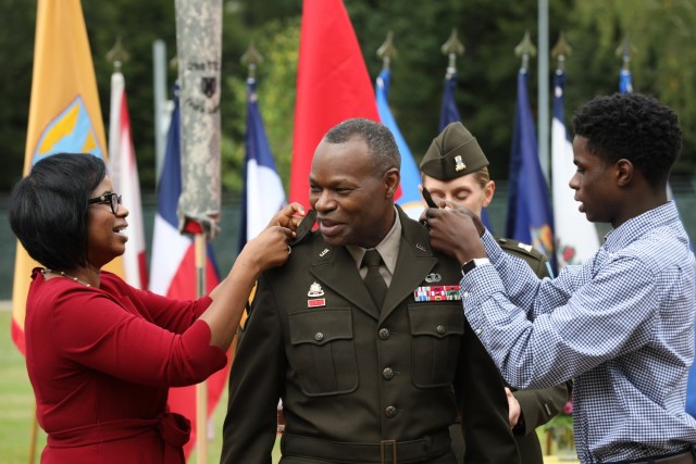 Maj. Gen. James Smith, commanding general, 21st Theater Sustainment Command, center, getting his new rank pinned on the shoulders of his Army Green Service Uniform by his wife Catrina, left, and his son Jalen, right, Sept. 16 on Panzer Field at...