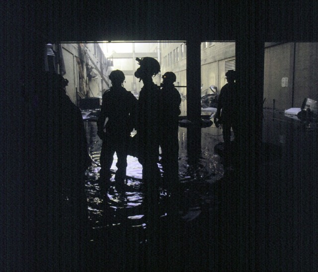 Members of the Military District of Washington (MDW) Engineer Company (Technical Rescue) walk into the causeway between E ring and D ring of the Pentagon on September 12, 2001. They were in the middle of a secondary search for bodies, and just finished searching their sector of the D ring. The morning before, in an attempt to frighten the American people, five members of Al-Qaida, a terrorist group of fundamentalist Muslims, hijacked American Airlines Flight 77, then flew a circuitous route returning to Washington and impacting the Pentagon killing all 64 passengers onboard and 125 people on the ground. The impact destroyed or damaged four of the five rings in that section of the building. Firefighters fought the fire through the night. (Photo courtesy of National Archives)