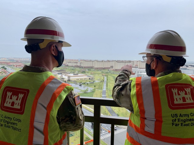 Brig. Gen. Kirk Gibbs (left), U.S. Army Corps of Engineers Pacific Ocean Division commander, listens to Col. Christopher Crary (right), Far East District commander, as they look from the balcony of the newly constructed Army Family Housing Towers...