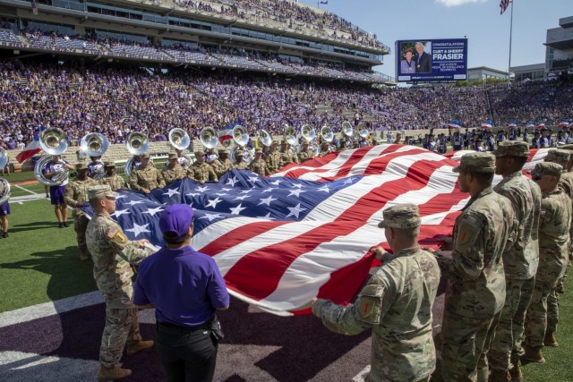 1st Infantry Division Soldiers unfurls the U.S. Flag during the half-time show on the Kansas State University’s football field on Fort Riley Day at the Bill Snyder Family Stadium, Manhattan, Kansas, September 18, 2021. The Soldiers in attendance...