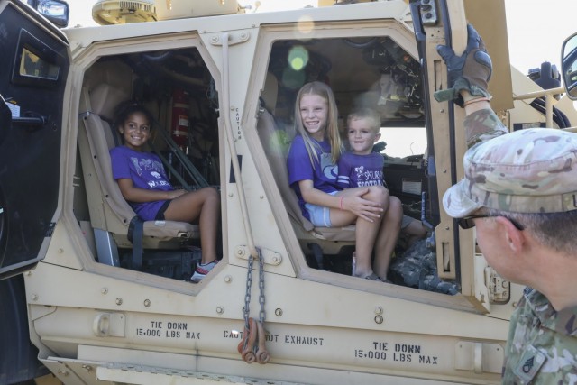 Children smile and pose for a photo on the military equipment static displays provided by the 1st Infantry Division for the Kansas State University’s Fort Riley Day events, September 18, 2001, in Manhattan, Kansas. The event honored the military for their service both at home and overseas. (U.S. Army photo by Spc. Catherine Bravo, 19th Public Affairs Detachment)