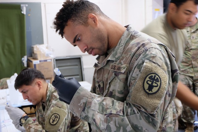 Spc. Rashawn Shepperd, foreground, and Sgt. Oscar Caro, draw syringes that will be used to administer measles, mumps and rubella syringes and chickenpox syringes to Afghan evacuees at Rhine Ordnance Barracks, Germany, Sept. 18. A diverse team of Army medical professionals vaccinated nearly 5,500 Afghan evacuees in less than 72 hours at ROB to protect them from the diseases and to help ensure the health and well-being of the military and local communities. Sheppard is a medical laboratory specialist assigned to the Ansbach Army Health Clinic, and Caro is a medical laboratory specialist, assigned to Public Health Command Europe.