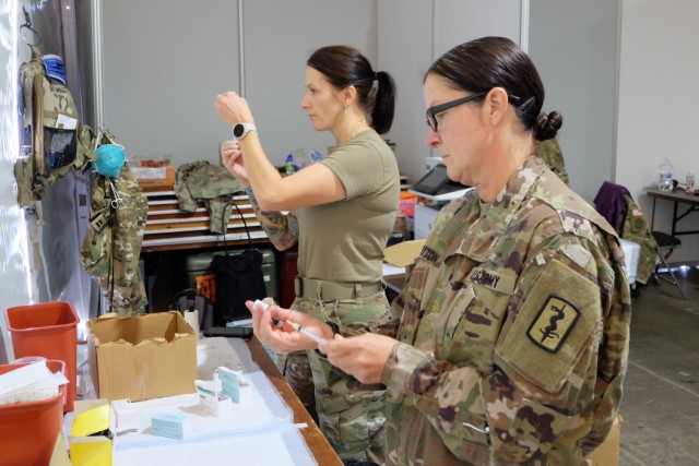 Maj. Laura Payton, foreground, and Capt. Jennifer Hensel, both Certified Registered Nurse Anesthetists from the 67th Forward Resuscitative Surgical Detachment, prepare measles, mumps and rubella syringes and chickenpox syringes to administer to Afghan evacuees at Rhine Ordnance Barracks, Germany, Sept. 18. A diverse team of Army medical professionals vaccinated nearly 5,500 Afghan evacuees in less than 72 hours at ROB to protect them from the diseases and to help ensure the health and well-being of the military and local communities.