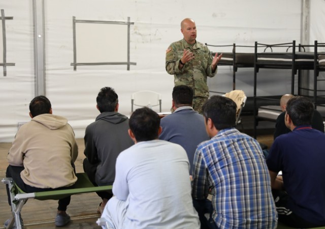 Spc. Carl Youngblood, 457th Civil Affairs, 7th Mission Support Command, 21st Theater Sustainment Command, welcomes Afghan travelers to "Intro to the USA" at Rhine Ordnance Barracks, Kaiserslautern, Germany. The cultural integration class,...