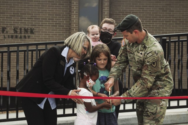 Stacye Downing, director, Fort Campbell Directorate of Family and Morale, Welfare and Recreation, and Col. Andrew Q. Jordan, Fort Campbell garrison commander, invite military children to help with a ribbon cutting Sept. 16 during the grand reopening of the Robert F. Sink Memorial Library. Renovations include new paving, carpeting, shelves and expanded children’s room.