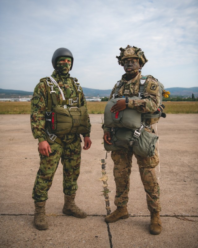 A U.S. Army paratrooper assigned to the 54th Brigade Engineer Battalion (Airborne) stands with a Serbian special operations paratrooper from the 63rd Parachute Brigade for a photo before a joint airborne operation as part of Exercise Skybridge 21...