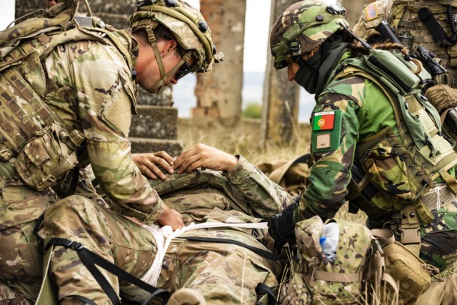 A U.S. Army Soldier assigned to Alpha Company, 1st Battalion, 16th Infantry Regiment “Iron Rangers,” 1st Armored Brigade Combat Team, 1st Infantry Division, and a Portuguese Soldier provide tactical medical care for a simulated casualty in...