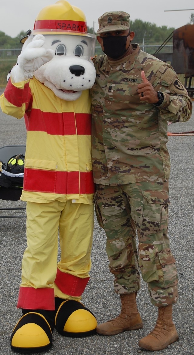 Command Sgt. Maj. Benjamin C. Lemon, U.S. Army Garrison Humphreys senior enlisted advisor, celebrates with Sparky the Fire Dog, Sept. 30, at the 2021 Fire Prevention Week Proclamation Ceremony at the fire department training area. (U.S. Army photo by Steven Hoover)