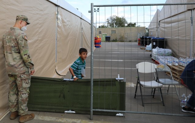 A young Afghan traveler "helps" with traffic flow at Rhine Ordnance Barracks in Kaiserslautern, Germany during Operation Allies Welcome. Security forces regularly patrol the temporary living areas and include MPs and engineers from 18th MP Brigade...
