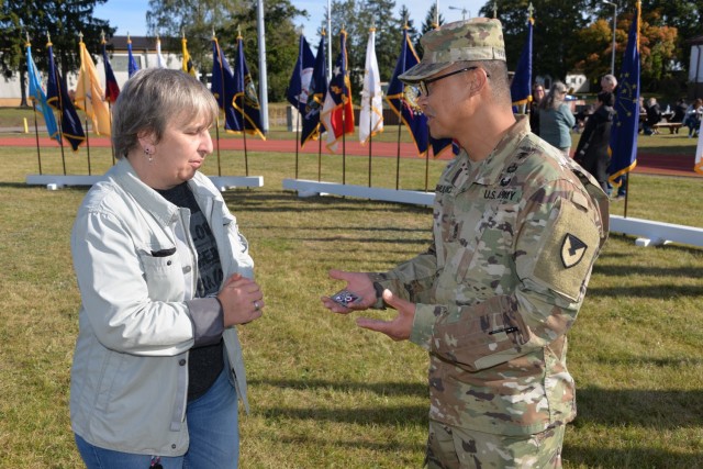 Marina Hilbert, left, receives a commander&#39;s coin from Sgt. Maj. Francis Famularcano, sergeant major for U.S. Army Medical Materiel Center-Europe. Hilbert maintains a website that provides information and nostalgic photos about the Husterhoeh Kaserne. USAMMCE recently moved from the kaserne after having been at the installation since 1975.