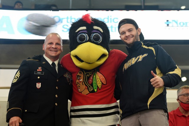 Sgt. Maj. Dennis Koski, left, operations sergeant major for the 85th U.S. Army Reserve Support Command, and U.S. Navy Veteran Lt. j.g. Ash Davis, meet Tommy Hawk, the Chicago Blackhawks’ mascot, after a military recognition during a Chicago...