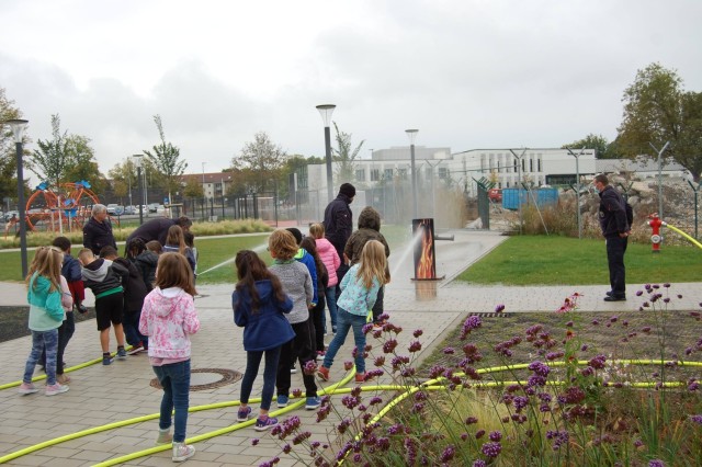 The U.S. Army Garrison Wiesbaden fire department crew help children at the Wiesbaden Elementary School take turns putting out a flame during fire prevention week observances Oct. 4. (Photo by Keyrstyn Drake with the Wiesbaden High School Junior...