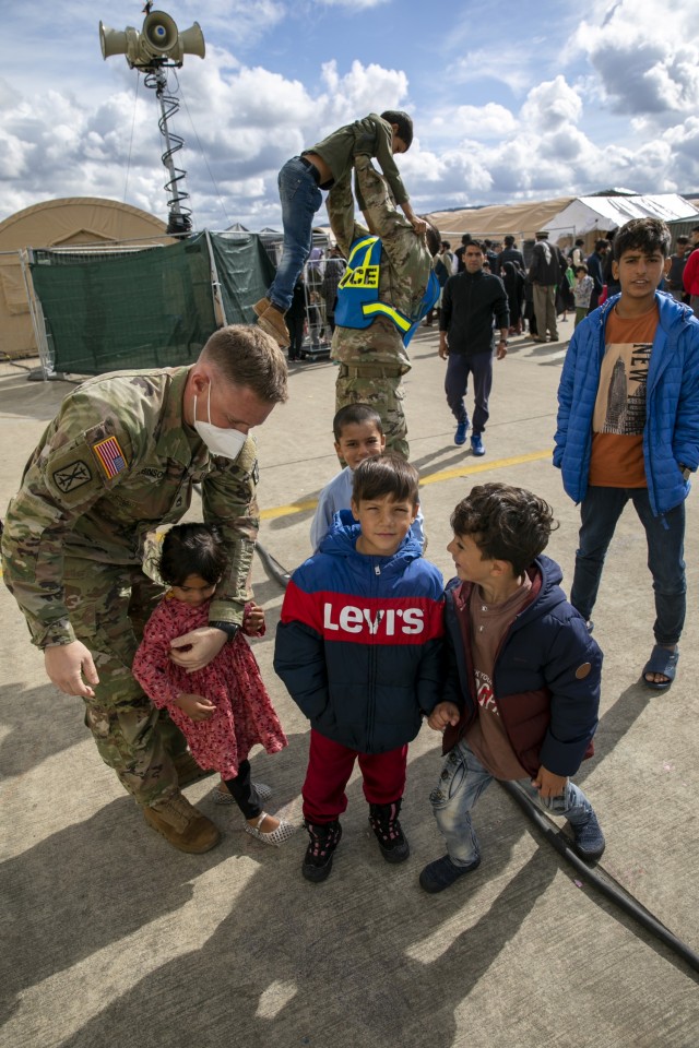 Soldiers assigned to 1st Battalion, 77th Field Artillery Regiment, play with Afghan children in the courtyard at Ramstein Air Base, Germany while conducting gate guard and security patrols in the facilities on Sept. 30, 2021. Approximately 175 Soldiers from 1-77 FAR, 41st Field Artillery Brigade have been assigned to support Operation Allies Welcome and augment the security force at the holding facilities at Ramstein providing life support for Afghan travelers awaiting follow on flights. (Official U.S. Army photo by Spc. Ryan Barnes)