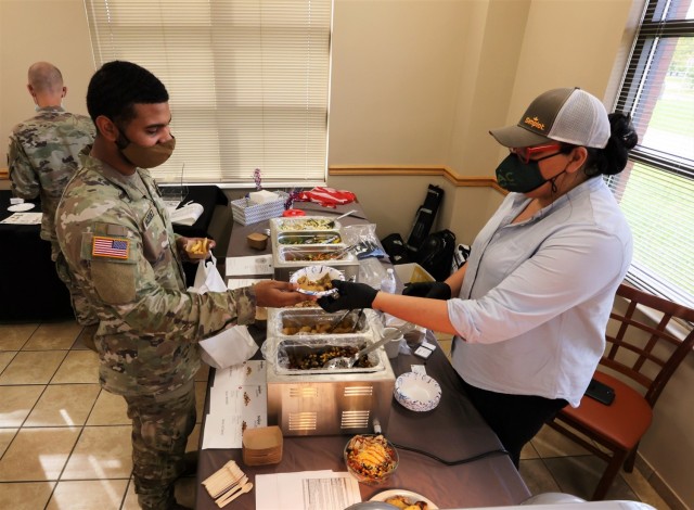 A vendor hands Spc. Antonio Vazquez a potential new menu option during a tasting event in Cantigny Dining Facility Oct. 5, 2021. Attendees were encouraged to share their opinions on comment cards to help decide which healthy options will be added to Fort Knox dining facilities.