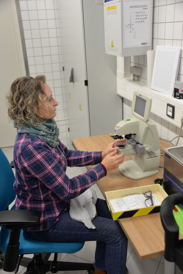 Yvonne Gortner,  prescription eyeglass maker supervisor for the U.S. Army Medical Materiel Center-Europe, examines a custom lens to make certain it is correctly ground. Gortner has been with USAMMCE since 2003, beginning as an optician.