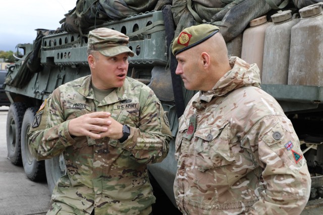 Warrant Officer Steven Mulhearn (right), Command Sgt. Maj. of the 1st Armoured Infantry Brigade (UK), and Command Sgt. Maj. Benjamin Pingel of the 2nd Cavalry Regiment, talk about the similarities and differences of their units at a static display...