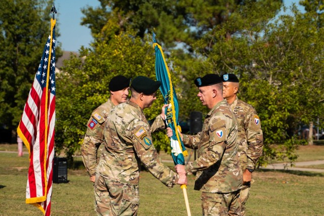 Brig. Gen. Garrick Harmon passes the U.S. Army Security Assistance Training Management flag to Col. Andrew Clark (left), officially transferring command of SATMO to Clark from Lt. Col. Alex Duran (far right), during a Sept. 29 ceremony at SATMO headquarters, Fort Bragg, North Carolina.   (Photo by Staff Sgt. Tyrone Wilson)