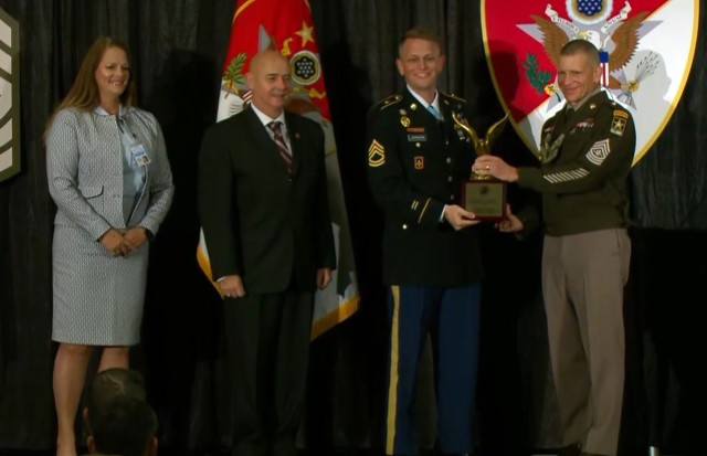 Sgt. Maj. of the Army Michael A. Grinston, right, presents the Sgt. Maj. Larry L. Strickland Educational Leadership Award to Sgt. 1st Class Brandon Johnson, second from right, assigned to the 11th Missile Defense Battery, 10th Army Air and Missile Defense Command, during the Sergeant Major of the Army Forum and Awards Ceremony in Washington, D.C., Oct. 11, 2021.