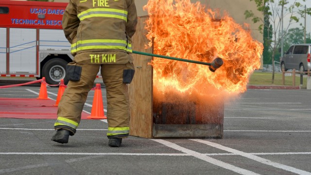 A USAG Daegu firefighter splashes water on an oil fire as part of a live demonstration in support of Fire Prevention Week. The event was just one of many hosted by USAG Daegu Emergency Services during an open house on October 9th, 2021.