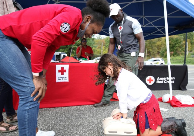 American Red Cross Greater New York Region members Kaba Sanasa (left) and Alexander Poku (background) give guidance to 7-year-old Vivian McGehee while she was performing cardiopulmonary resuscitation during the Emergency Preparedness Fair and National Night Out event Saturday at West Point.