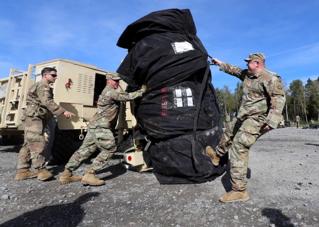 GRAFENWOEHR, Germany – Staff Sgt. Kyle Mcguigan, left, from Brooklet, Georgia, prepares to assist Chief Warrant Officer 3 Chris Hoaglin, center, from Hastings, Michigan, and Maj. Daniel Pickering, right, from Sanford, Maine, with the unloading effort of one of V Corps' tents used during Warfighter 22-1 in Grafenwoehr, Germany, Oct. 1. The WFX 22-1 is V Corps' final certifying exercise in becoming the U.S. Army's fourth corps headquarters and America's forward deployed corps in Europe. (U.S. Army photos by Pfc. Devin Klecan/released)