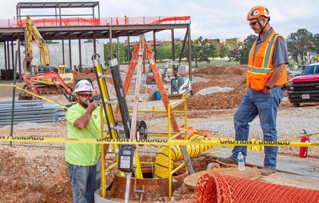 U.S. Army Corps of Engineers, Kansas City District Missouri Resident Office Hospital Low Voltage Quality Assurance Officer Ryan Snyder (right) works alongside the contracted low voltage quality control officer as he lowers wire underground on-site...