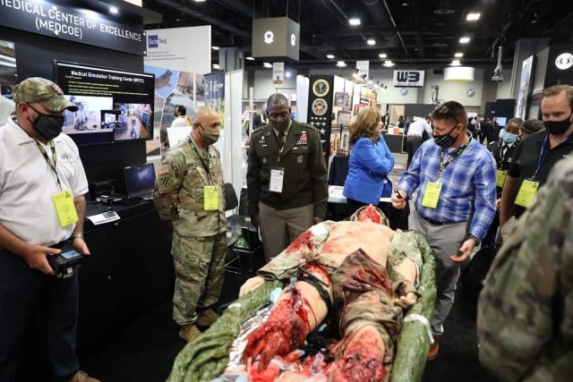 The U.S. Army Medical Center of Excellence, or MEDCoE, provided a participatory experience for attendees during the Association of the United States Army’s, or AUSA’s, Annual Meeting, October 11-13. Hundreds of Army senior leaders, industry leaders and other interested AUSA participants stopped by the MEDCoE kiosk for a fully interactive demonstration that highlighted the Tactical Combat Casualty Care Exportable, or TC3X, mannequin, offering an opportunity to see the simulation capabilities in action during live, hands-on exhibitions. Pictured: Lt. Gen. R. Scott Dingle (Center), the Surgeon General of the U.S. Army and Commanding General, U.S. Army Medical Command, or MEDCOM, receives TC3X demonstration from MEDCoE kiosk leads, Master Sgt. Kaleb Twilligear and James Kinser alongside Master Sgt. Rodel Gonzalez, Senior Enlisted Medical Simulation and Training Materiel Capability Developer, Program Executive Office, Simulation Training and Instrumentation, Medical Simulation, October 13, 2021.