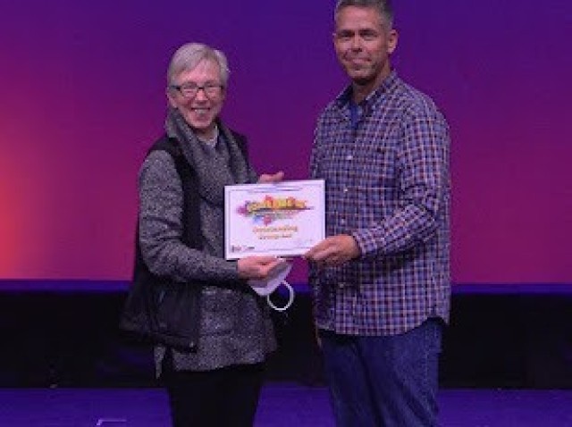 IMCOM Europe Command Sgt. Maj. Christopher Truchon presents Vikki Hanrahan, USAG Ansbach entertainment director a certificate for the YouthFEST Best Group Performance for Ansbach Theatre Youth Troupe.