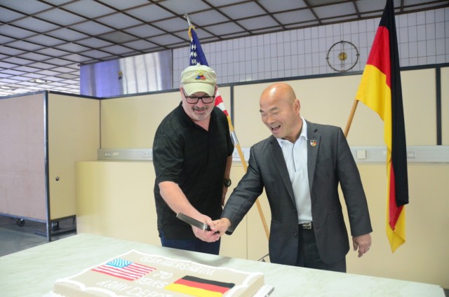 From left, Germersheim Army Depot Site Manager Leonard Chanler and Deputy Garrison Manager Jae Kim prepare to cut the cake celebrating 70 years of Army operations at the installation.