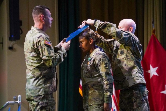 Fires Center of Excellence and Fort Sill Command Sgt. Maj. Stephen Burnley, left, and Sgt. 1st Class Justin Engle, Fort Sill Sergeant Audie Murphy Club president, present the Sergeant Audie Murphy Club medallion to Senior Drill Sergeant (Staff Sgt.) Shanika Haws. The induction ceremony was Oct. 15, 2021, at Kerwin Auditorium in Snow Hall.