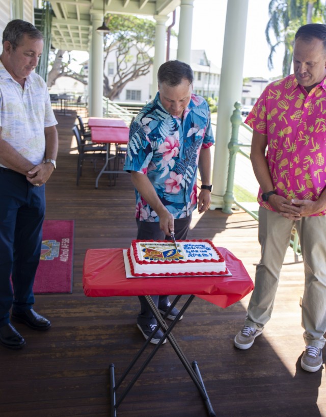 The 402nd Army Field Support Brigade deputy to the commander Joe Schulz (left) and 402nd Command Sgt. Maj. Adam Lepley, look on as 402nd commander, Col. Erik Johnson, cuts the cake during the brigade’s 15th birthday celebration on Oct. 15, 2021....