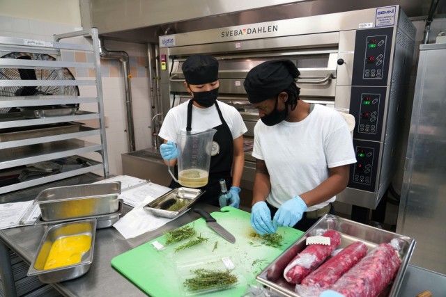 Spc. Nhien Nguyen (left) and Sgt. Tashauna Walls (right), Field Feeding Platoon, 35th Combat Sustainment Support Battalion, 10th Support Group, prepare herb encrusted ribeye, during the Japan-wide Joint Culinary Competition, held Oct. 20-21, Camp Foster, Okinawa, Japan. The team competed against three other teams from the U.S. Marine Corps, Navy, and Air Force, to take home the first-place prize for the second time in a row.