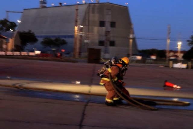 Firefighters drag a mannequin away from a helicopter toward the firetruck on Fort Sill’s Henry Post Army Air Field during training Oct. 20, 2021.