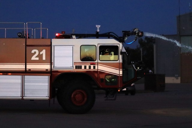 The firetruck from Station #2 leaves the station with the water spraying in front of the truck to get the water on the fire quicker during nighttime aircrew evacuation training Oct. 20, 2021 at Henry Post Army Air Field.