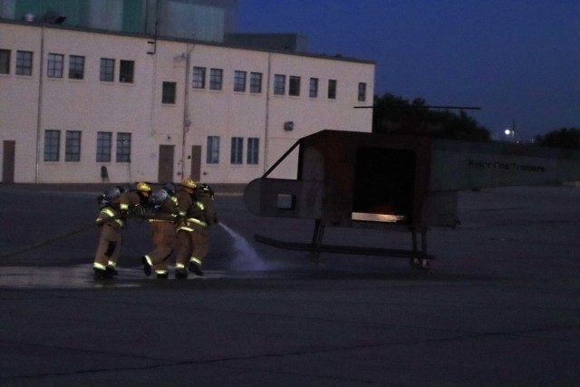 While already spraying water, firefighters drag the hose over to a prop helicopter to put out any fire so they can get to the aircrew (mannequin) inside on Fort Sill’s Henry Post Army Air Field during training Oct. 20, 2021.