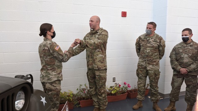 U.S. Army Maj. Shawn Pyer, former commander of the 142nd Medical Company, presents a riding crop that belonged to Lt. Col. Michael Myslinski, the unit's first commander after reconstitution, to the current commander Maj. Amanda Griffiths at the Army Aviation Support Facility in Windsor Locks, Conn. on Oct. 24, 2021. The unit was mobilizing in support of Operation Atlantic Resolve and heading to Texas before deploying to Poland. The riding crop was used by Myslinski as a prop in an unofficial command photo.