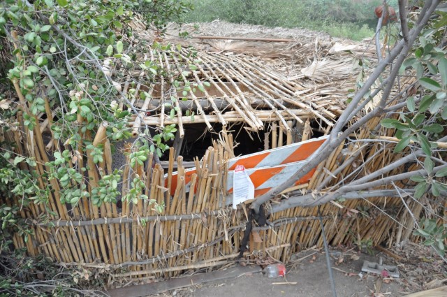 An abandoned Arundo donax hut partially hidden on the wooded bank is revealed as contracted workers removed tons of trash from San Jose Creek. Arundo is an invasive giant reed that grows very fast. The U.S. Army Corps of Engineers Los Angeles...