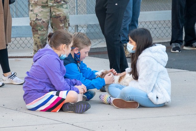 Tiny family members of Soldiers assigned to the 142nd Medical Company sit on the ramp of the Army Aviation Support Facility in Windsor Locks, Conn. on Oct. 24, 2021, to play with a dog as the unit prepared to mobilize in support of Operation Atlantic Resolve.