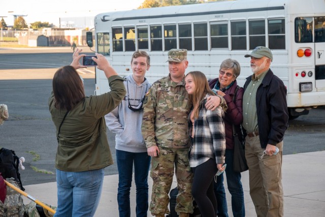 Platoon Sergeant, Sgt. 1st Class Doug Kohlun poses with his family for a picture at the Army Aviation Support Facility in Windsor Locks, Conn. on Oct. 24, 2021. His unit, the 142nd Medical Company, was mobilizing in support of Operation Atlantic Resolve and heading to Texas before deploying to Poland.