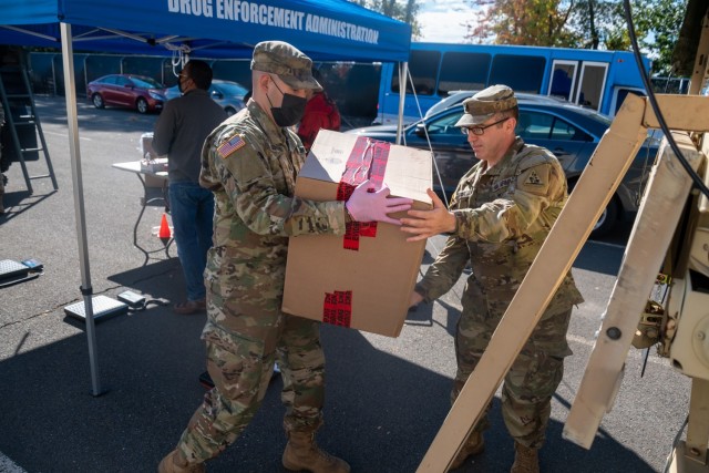 U.S. Army Sgt. Donovan Benitez hands Staff Sgt. Michael Beers a box of prescription drugs to load on the back of a Light Medium Tactical Vehicle during National Prescription Drug Take Back Day in Rock Hill, Connecticut Oct. 23, 2021. This nationwide event was created by the DEA to help dispose of old, expired, or unwanted drugs in order to help reduce the possibility of their misuse. At the end of the event, all the turned in drugs were destroyed at an incinerator.