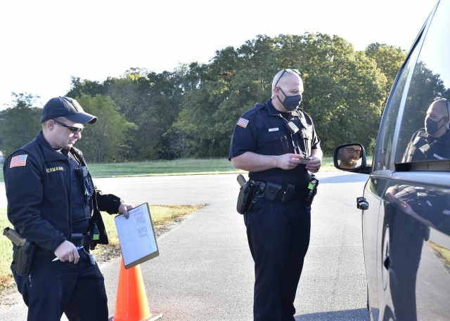 Fort Leonard Wood Directorate of Emergency Services Police Officers Matthew Hermann (left) and Joshua Dahms speak with an on-post driver during a random checkpoint Friday in the parking lot of the Lieber Heights Swimming Pool on Turner Street. The...