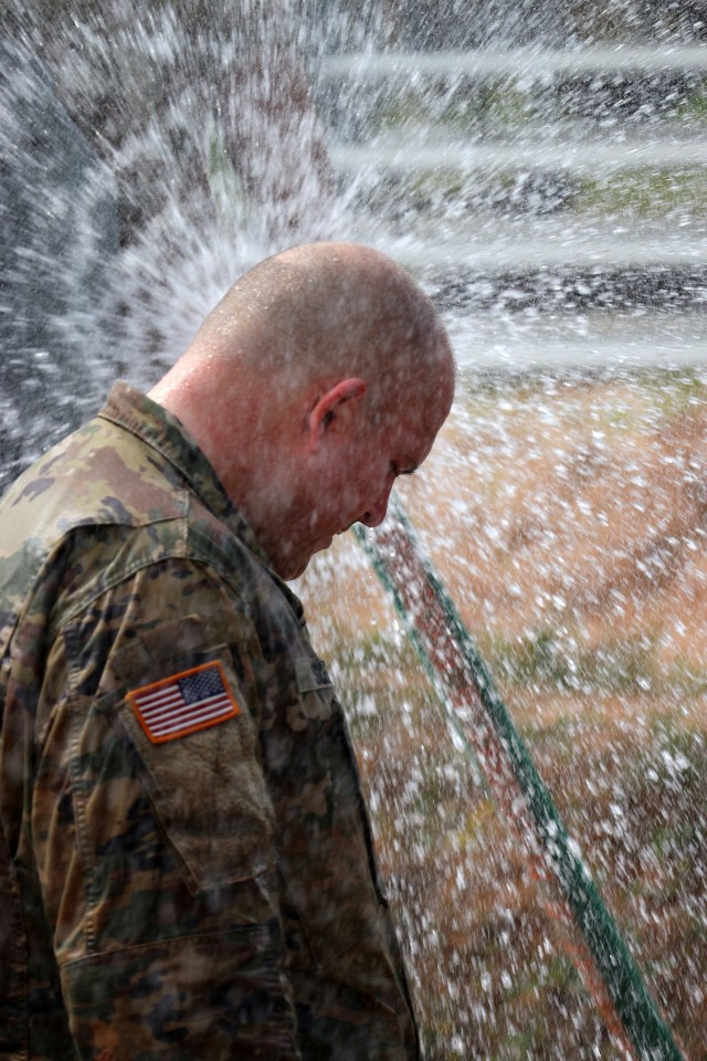 A competitor rinses off and cools off after crawling through the mud pit during the 1st Cyber Battalion "mungadai" 24-hour challenge, at Fort Gordon, Ga., Oct. 22, 2021. (Photo by Bill Roche)