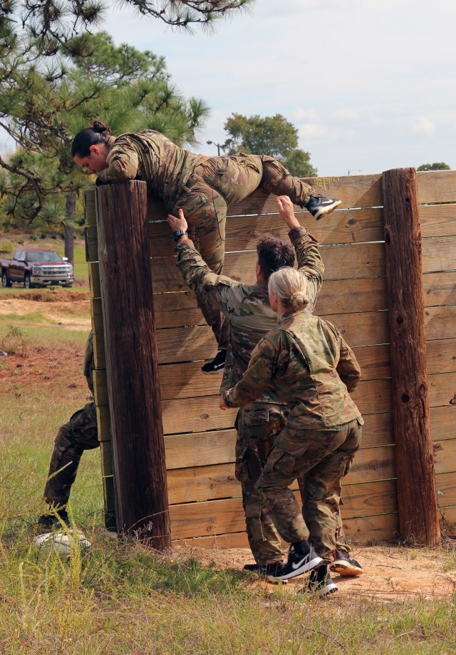 A team works together to scale a wall at the start of the three-mile "Marine Mudder" obstacle course competition of the 1st Cyber Battalion "mungadai" 24-hour challenge, at Fort Gordon, Ga., Oct. 22, 2021. (Photo by Bill Roche)