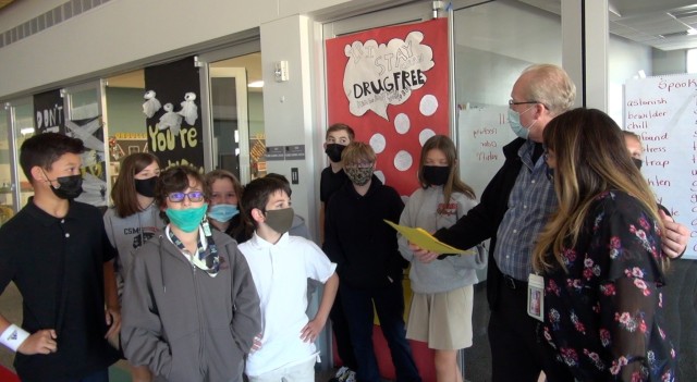 Joe Bubala presents Annette Hathaway and her homeroom class a certificate and swag for winning the best-decorated door marking Red Ribbon Week at Col. Smith Middle School.