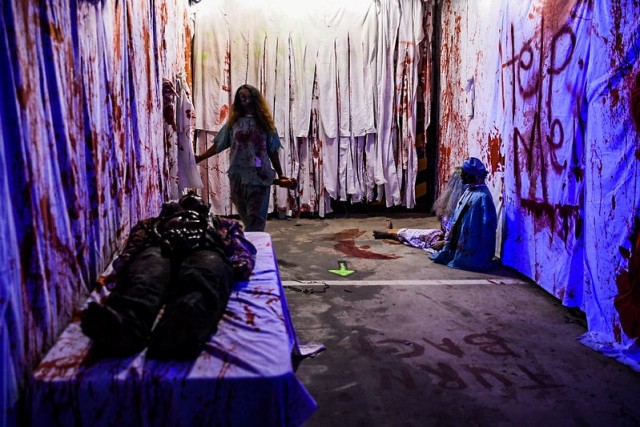 A volunteer walks the bloody psych ward in the House of Fears haunted house during the Camp Humphreys Halloween Spooktacular, hosted by the Family and Morale, Welfare, and Recreation office and Better Opportunities for Single Soldiers program, at Sitman Gym parking garage Oct. 30, 2021. (U.S. Army photo by Spc. Brooke Davis)