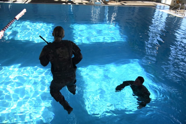 Sgt. Lauren Roper, a noncommissioned officer in charge of an Army Space Control Planning Team in 2nd Space Company, 1st Space Battalion, 1st Space Brigade, U.S. Army Space and Missile Defense Command, leaps into a pool with a fellow Soldier assisting as a safety swimmer, as part of the company’s annual combat water survival training, which familiarizes Soldiers in deep water in case of emergency, at Fort Carson, Colorado, Oct. 29, 2021. (U.S. Army photo by Sgt. 1st Class Aaron Rognstad/RELEASED)