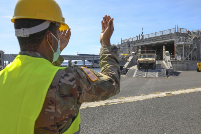 Staff Sgt. Kyron Brown, a transportation management coordinator with the 627th Movement Control Team, guides military vehicles off the roll-on-roll-off ramp of the USNS Yuma in the port of Gazenica in Zadar, Croatia on May 3, 2021. This was the first delivery of what will be 300 pieces of military equipment moved to Croatia for use during exercise DEFENDER-Europe 21. (U.S. Army photo by Sgt. Joshua Oh)