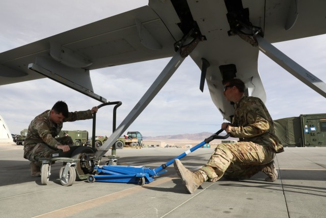 U.S. Army Sgt. Kristian Milke, and U.S. Army Pfc. Tyler Landers, both MQ-1C Gray Eagle maintainers with Fox Company, 1st Attack Battalion, 1st Combat Aviation Brigade, load a Gray Eagle onto a dolly to be rolled into a hangar for protection from...